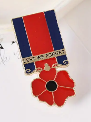 Pin with red poppy flower and 'Lest We Forget' inscription on a white background
